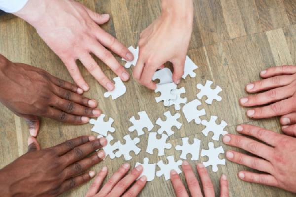Hände, die gemeinsam an einem Puzzle arbeiten